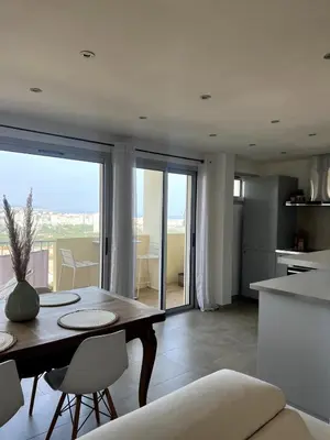 a kitchen and living room with a table and chairs at Lea's cozy nest with a sea-mountain view in Saint-Laurent-du-Var