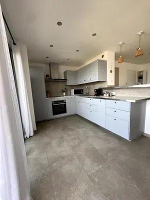 a kitchen with white cabinets and a tile floor at Lea's cozy nest with a sea-mountain view in Saint-Laurent-du-Var