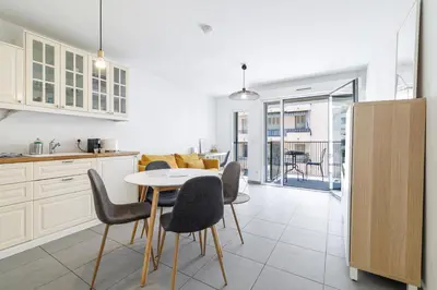 a kitchen with white cabinets and a white table and chairs at Charmant 2 pièces lumineux Quartier du Port in Nice