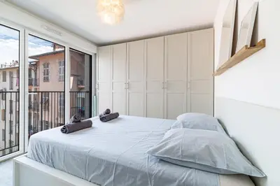 a bedroom with a large bed and a kitchen at Charmant 2 pièces lumineux Quartier du Port in Nice