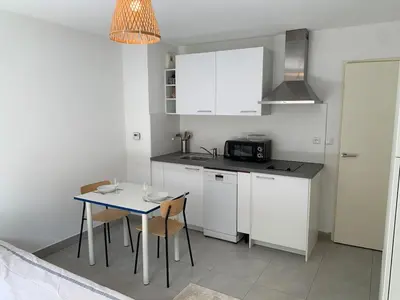 a kitchen with white cabinets and a table with chairs at Joli studio, quartier du port in Nice