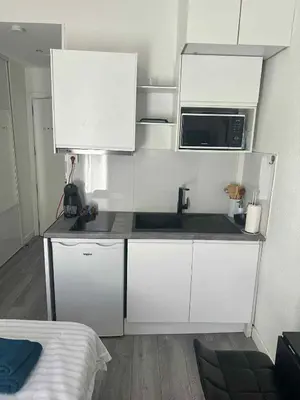 a small kitchen with white cabinets and a microwave at joli studio en face de la gare in Nice