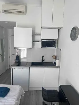 a small kitchen with white cabinets and a microwave at joli studio en face de la gare in Nice