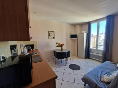 a kitchen with wooden cabinets and a table with a vase of flowers at Le Centrale - Place Masséna in Nice