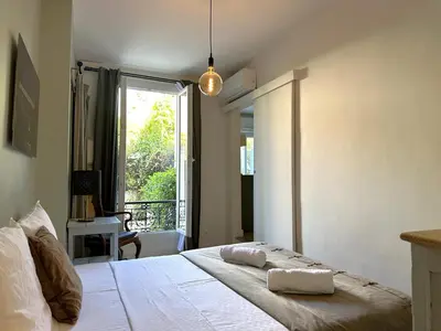 a bedroom with a white bed and a window at Cocon Provençale à 5 min de la mer in Nice