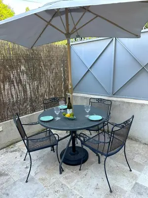 a table with two chairs and an umbrella at Cocon Provençale à 5 min de la mer in Nice