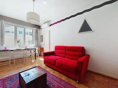 a living room with a red chair and a table at Apartment Daphné by Interhome in Nice