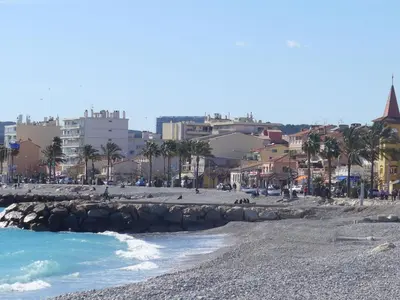 a beach with palm trees and buildings in the background at Apartment Le Persépolis by Interhome in Cagnes-sur-Mer