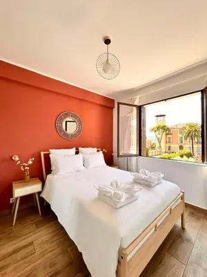 a bedroom with a large bed with an orange wall at Near Port & City - Private Parking & Breakfast - Full apartment in Nice