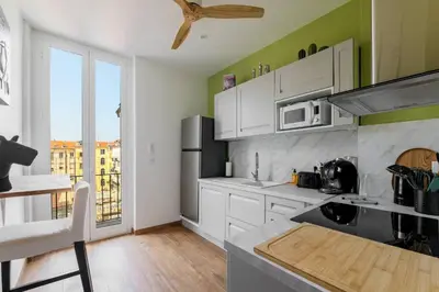 a kitchen with white cabinets and a large window at Elegant et lumineux 3 pieces Avenue Jean Medecin in Nice