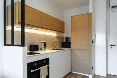 a kitchen with white counters and wooden cabinets at Magnifique studio boulevard Gambetta - B in Nice