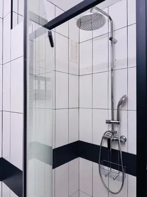 a shower in a bathroom with black and white tiles at LE CARRAS - Proche de aéroport , Plage à pied - Promenade des anglais in Nice