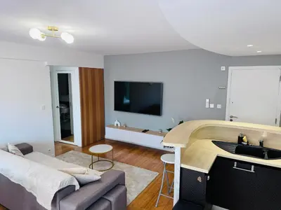 a living room with a couch and a tv at LE CARRAS - Proche de aéroport , Plage à pied - Promenade des anglais in Nice