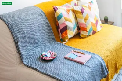 a blanket on a couch with a book and a bowl at The cozy corner of Amelie in Nice
