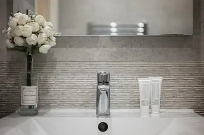 a bottle of perfume and a vase of flowers on a sink at Soleil Sucré - Splendid cocoon near Jean Médecin in Nice