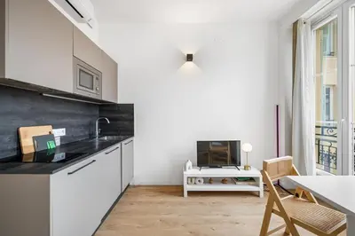 a kitchen with white cabinets and a black counter top at Soleil Sucré - Splendid cocoon near Jean Médecin in Nice