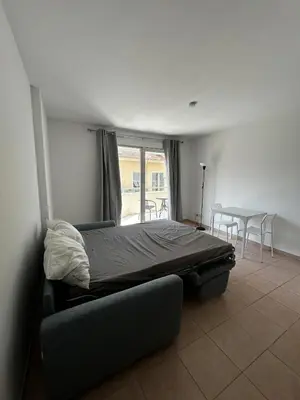 a bedroom with a bed and a table and a kitchen at Studio bord de plage à Nice in Nice