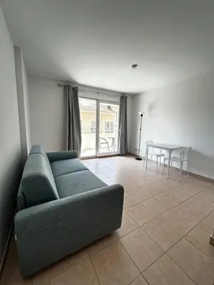 a living room with a blue couch and a table at Studio bord de plage à Nice in Nice