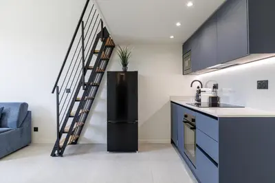 a kitchen with a black refrigerator and a staircase at PLACE MASSENA Coulée Verte in Nice