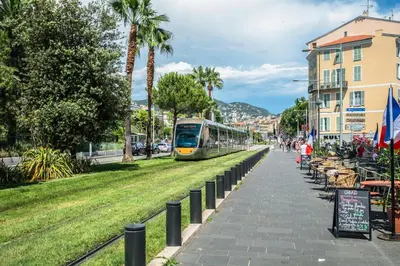 a train traveling down a street next to a sidewalk at PLACE MASSENA Coulée Verte in Nice