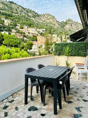 a black table and chairs on a patio with a view at Azure Horizons Seaside Escape in Beaulieu-sur-Mer
