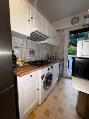 a kitchen with white cabinets and a washing machine at Azure Horizons Seaside Escape in Beaulieu-sur-Mer