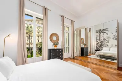 a white bedroom with a bed and a large window at Sumptuous Art Deco Apartment - 6 People in Nice