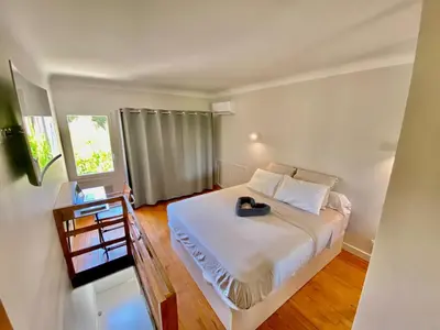 a bedroom with a large white bed and a window at Duplex 1 min de la plage in Beaulieu-sur-Mer