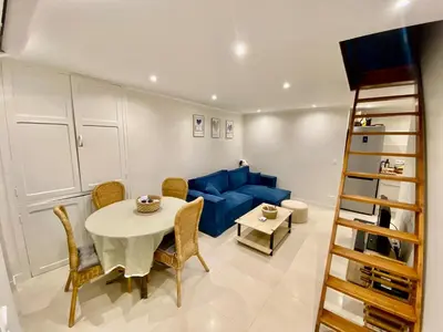 a living room with a table and a blue couch at Duplex 1 min de la plage in Beaulieu-sur-Mer