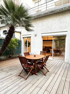 a wooden table and chairs on a deck with a palm tree at Appartement LOFT in Nice