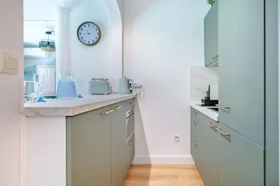 a kitchen with a sink and a clock on the wall at Studio Jardin Parking et Clim in Nice