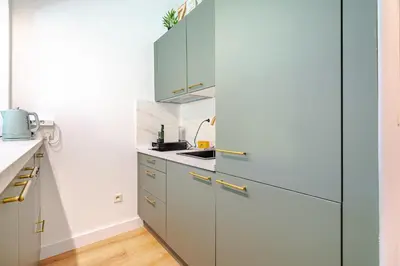 a kitchen with white cabinets and a blue refrigerator at Studio Jardin Parking et Clim in Nice