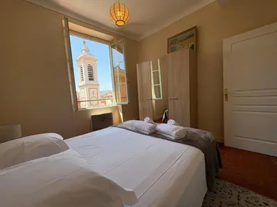a bedroom with two beds and a window with a clock tower at STE REPARATE - Cosy 2 pieces vue cathedrale in Nice