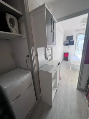 a small kitchen with white cabinets and a refrigerator at Studio à 5min de la plage in Nice