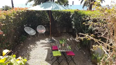 a patio with a table and chairs under an umbrella at Stunning flat with sea view & garden on Promenade dA in Nice