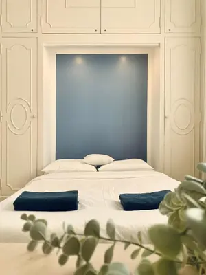 a white bed with two blue pillows on it at Stunning flat with sea view & garden on Promenade dA in Nice