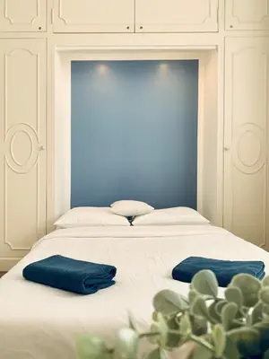 a white bed with two blue pillows on it at Stunning flat with sea view & garden on Promenade dA in Nice