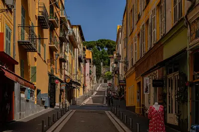 an alley with buildings and a woman walking down a street at Le Toit d'Azur in Nice