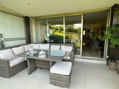 a patio with a table and wicker furniture on a porch at Spacieux appartement, Jardin, vue mer, calme in Nice