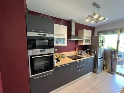 a kitchen with gray appliances and a red wall at Spacieux appartement, Jardin, vue mer, calme in Nice
