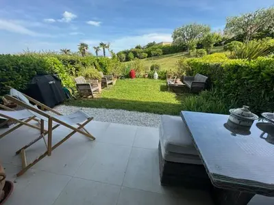 a patio with a table and chairs in a garden at Spacieux appartement, Jardin, vue mer, calme in Nice