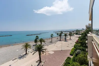 a view of a beach with palm trees and the ocean at Sea View- Beach- Chic & Air-Conditioned in Saint-Laurent-du-Var