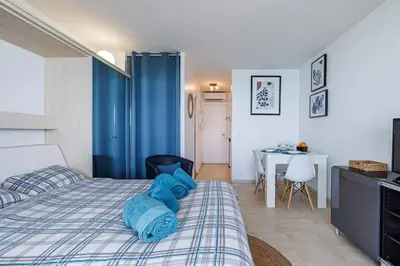 a bedroom with a bed with blue sheets and a table at Sea View- Beach- Chic & Air-Conditioned in Saint-Laurent-du-Var