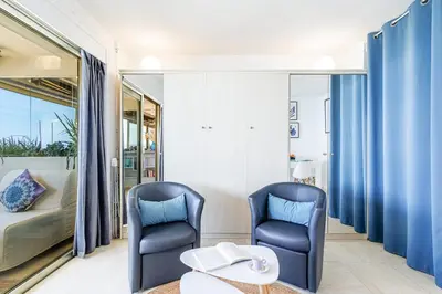 two blue chairs in a room with a bed and a table at Sea View- Beach- Chic & Air-Conditioned in Saint-Laurent-du-Var