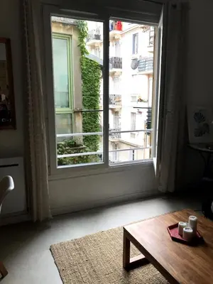a room with a large window and a wooden coffee table at charmant 2 pièces in Nice