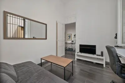 a living room with a bed and a table and a television at Nice et confortable 2 pièces cozy in Nice