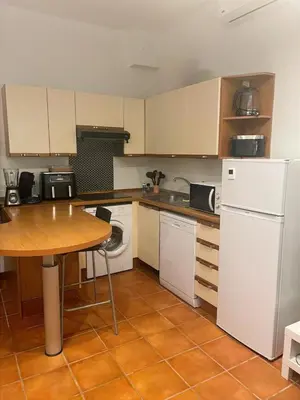 a kitchen with white appliances and a wooden table at Studio Carré d 'Or - 5 minutes de la mer in Nice