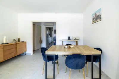a dining room with a wooden table and blue chairs at Happyfew La Suite Nicerama in Nice