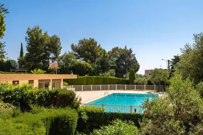 a swimming pool in a yard with bushes and trees at Happyfew La Suite Nicerama in Nice