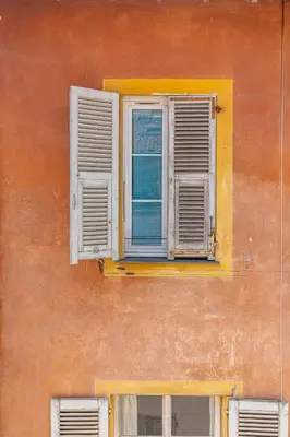an orange building with two windows with white shutters at La Vila-Vielha in Nice